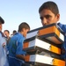 An Iraqi boy walks away after receiving soccer (football) shoes for his tea
