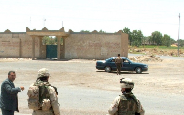 Soldiers stop the flow of traffic along a highway in taji