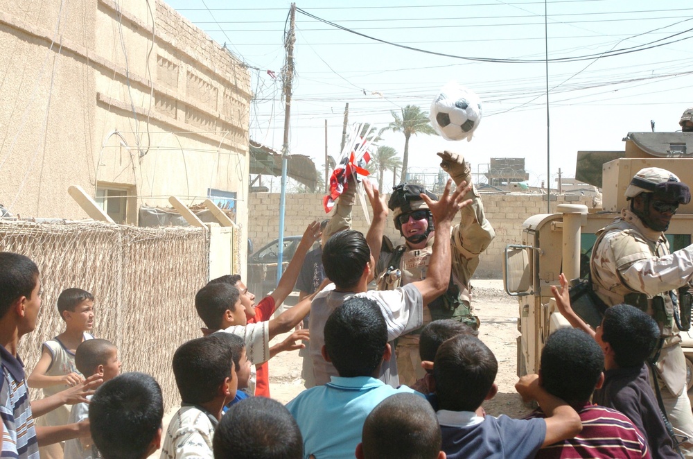 Capt. David Underwood hands out soccer balls to children