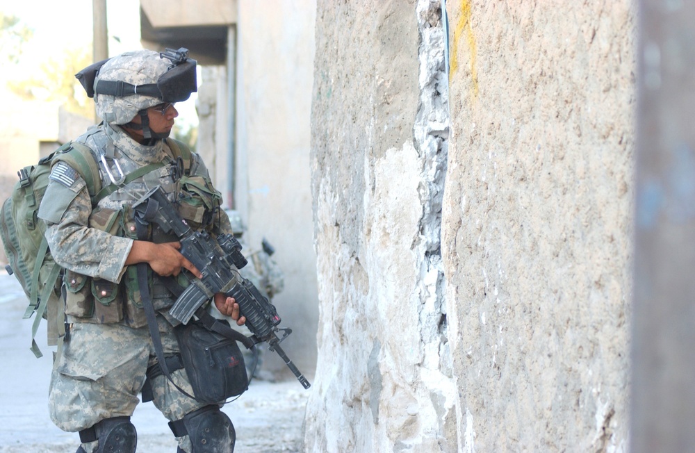 Pfc. Jeremy C. Ramirez pulls security outside of a house in Tall Afar