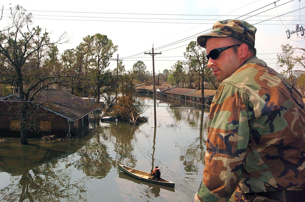 Spec. Joe Pavlansky sits atop the roof of house looking down