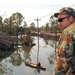 Spec. Joe Pavlansky sits atop the roof of house looking down