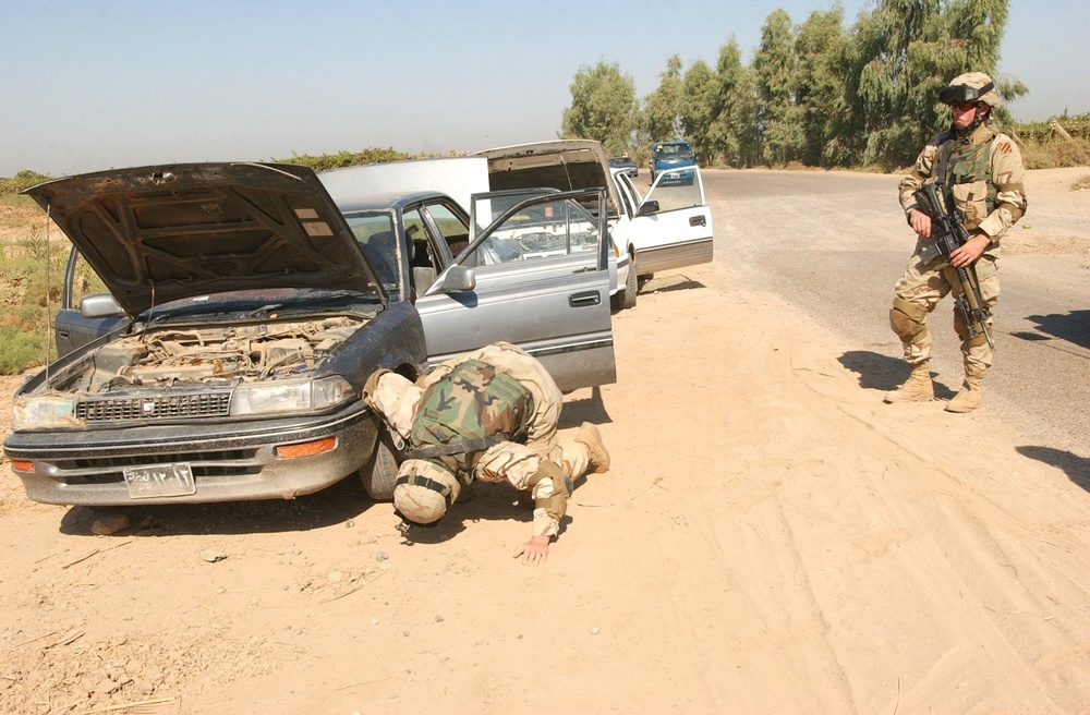 Soldiers search vehicles at a traffic check point