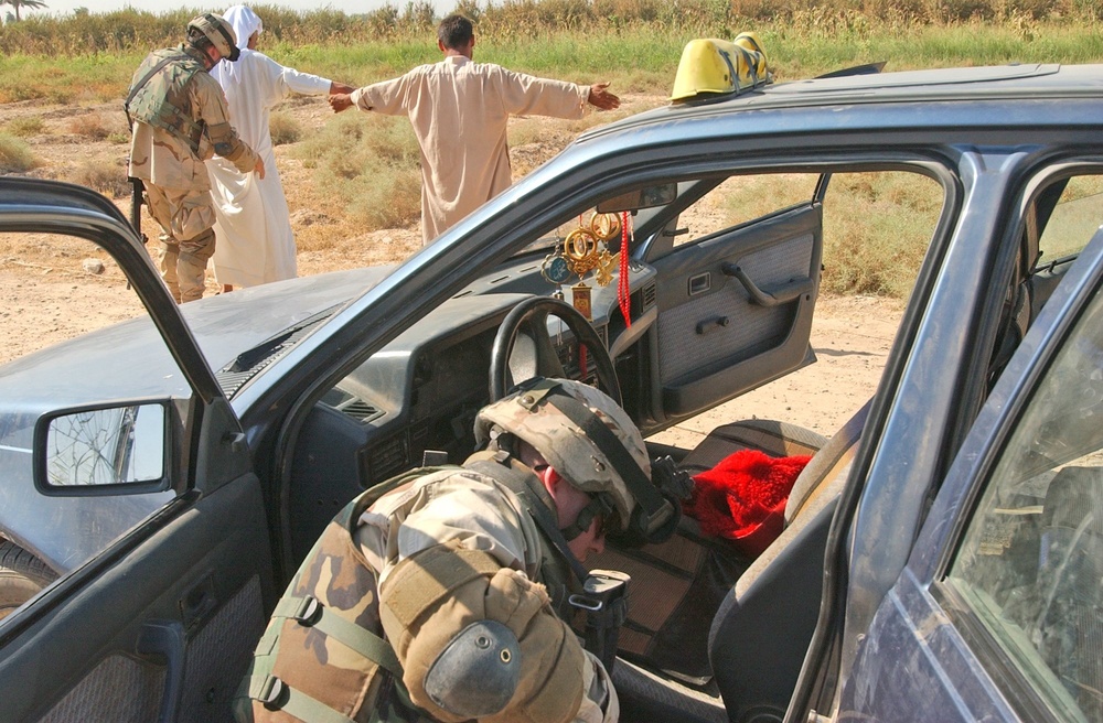 Soldiers search vehicles at a traffic check point