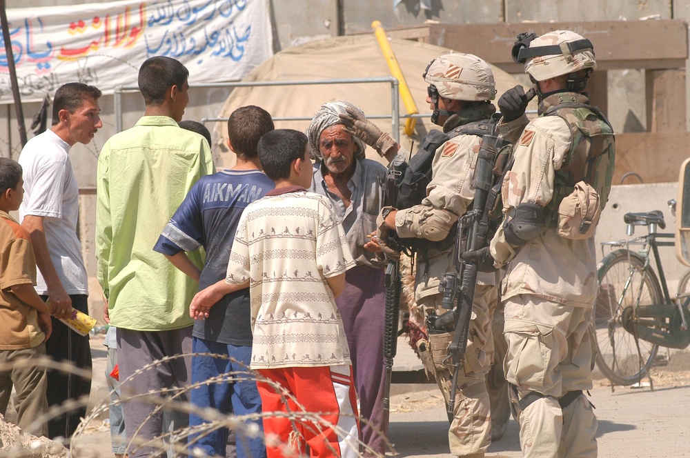 Soldiers talk with Iraqis while patrolling the city of Balad