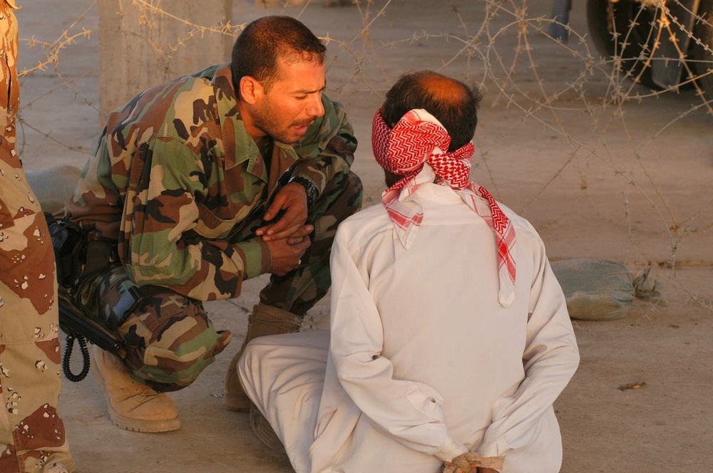 An Iraqi soldier questions a detainee