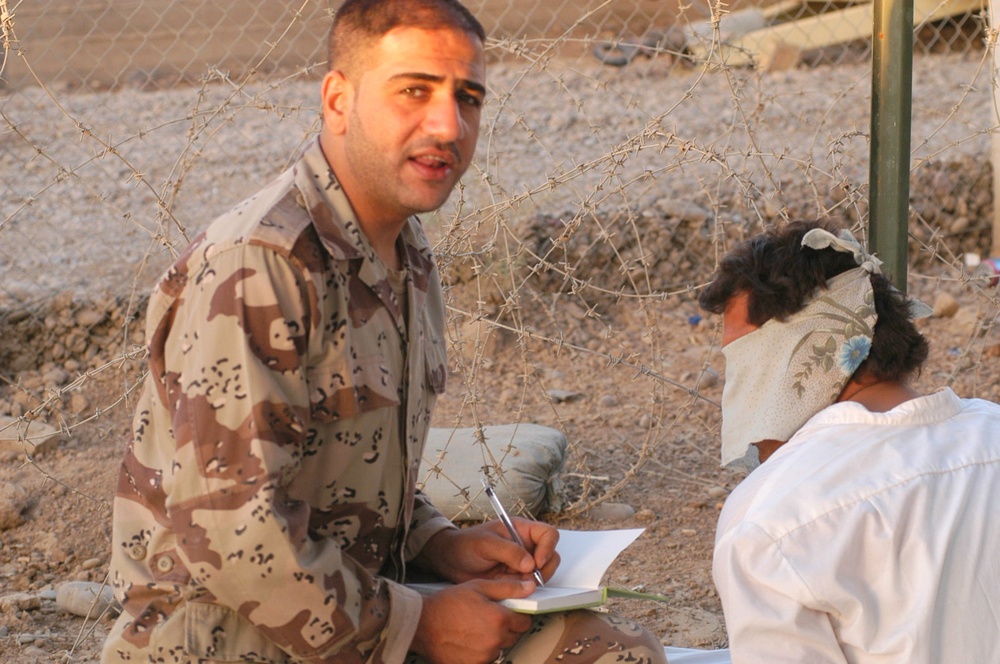 An Iraqi soldier talks to a detainee