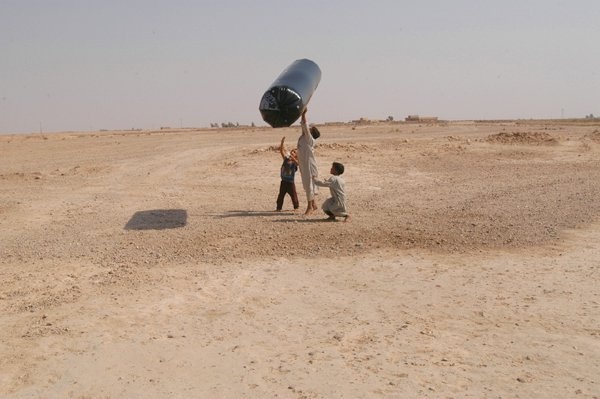 Iraqi children jump up to touch an inflatible toy