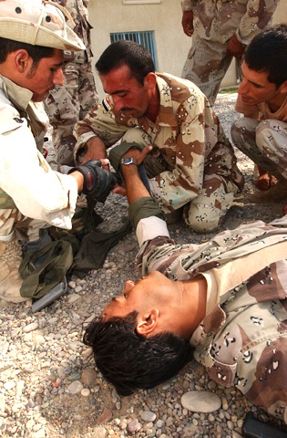 An Iraqi medic helps a fellow soldier practice treating another soldier for