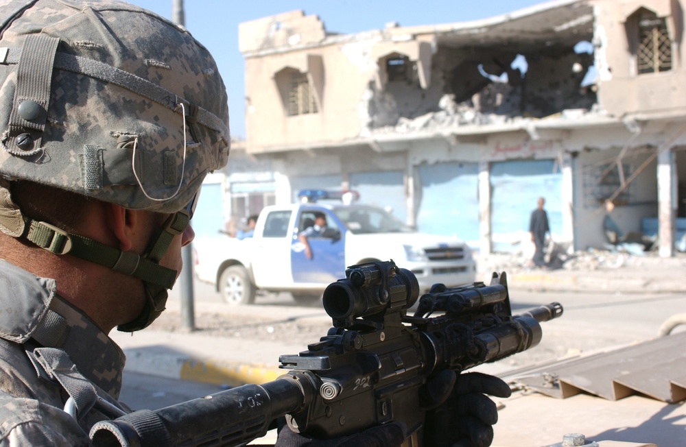 Pfc. Kevin L. White Watches as Vehicles Carrying Iraqi Police Forces Pass