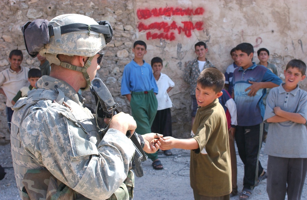 Pfc. John Reed gives a small metal pipe back to a young boy