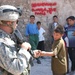 Pfc. John Reed gives a small metal pipe back to a young boy