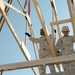 Soldiers prepare to put a truss on the roof of a warehouse