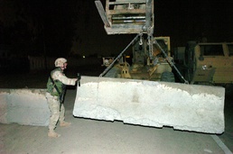 Capt. Scott Stine guides a concrete barrier into place
