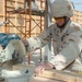 Spc. Matthew Bridges cuts a piece of wood