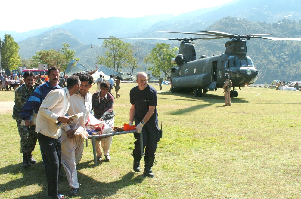 Members of Relief Agencies Carry an Injured Woman to  a U.S. Army UH-60 Bla