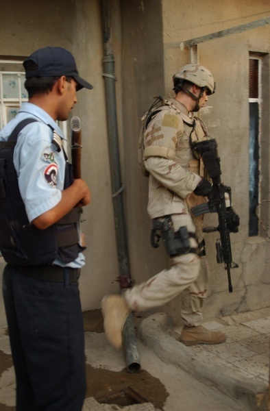 An Iraqi police officer and a Task Force Baghdad soldier search for terrori