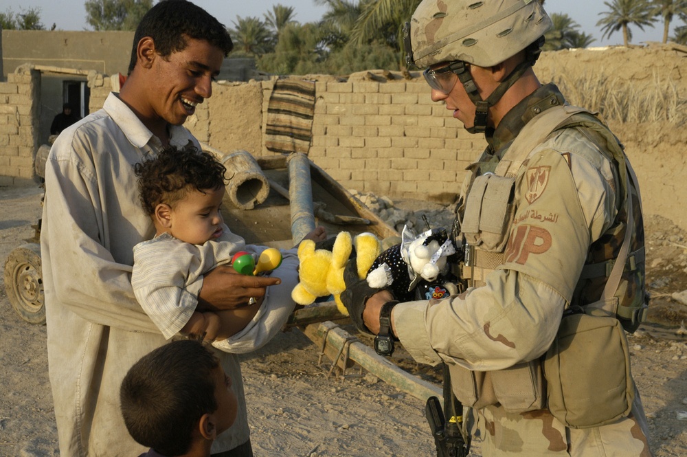 Sgt. Andrew Paasch passes out toys to a small Iraqi child