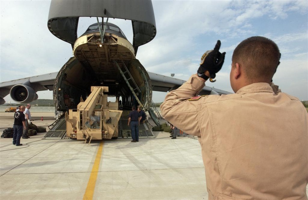 Senior Airman Patterson helps other crewmembers guide a crane onto a C-5 Ga