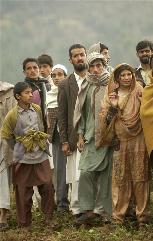 Village residents wait as Pakistani soldiers unload disaster relief supplie