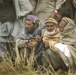 Village residents wait as Pakistani soldiers unload disaster relief supplie