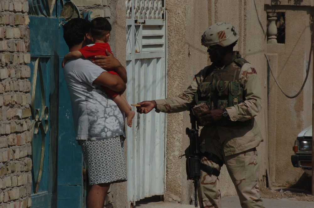 A Soldier shares his MRE with a young Iraqi girl