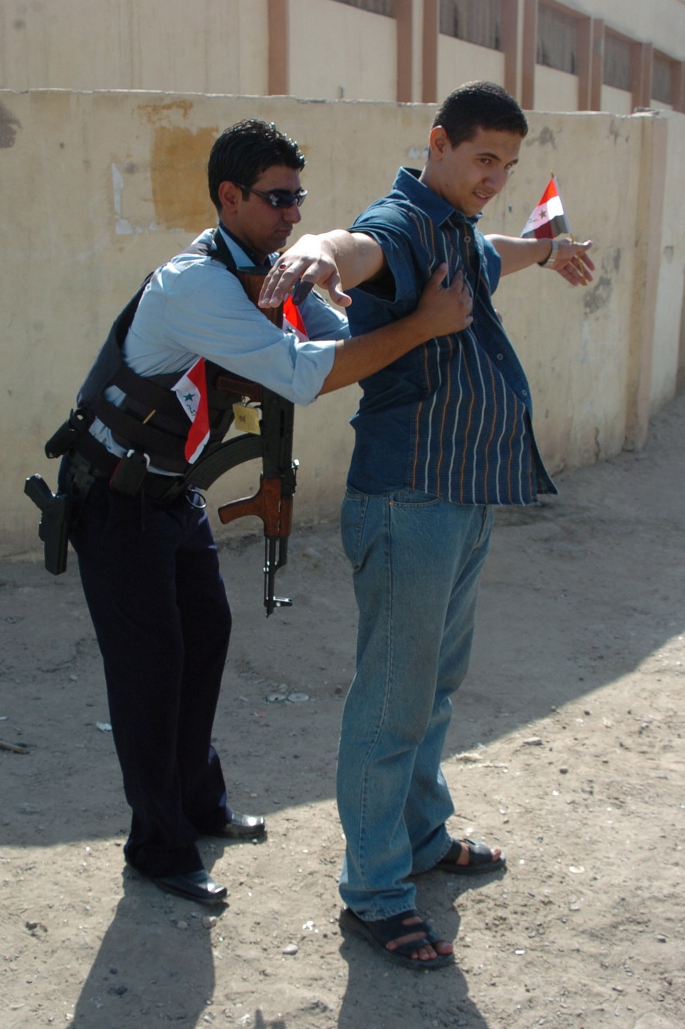 An Iraqi Police officer frisks a local resident