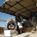 Two Soldiers help a local Iraqi man unload school supplies