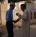 Security forces search an Iraqi with a wand