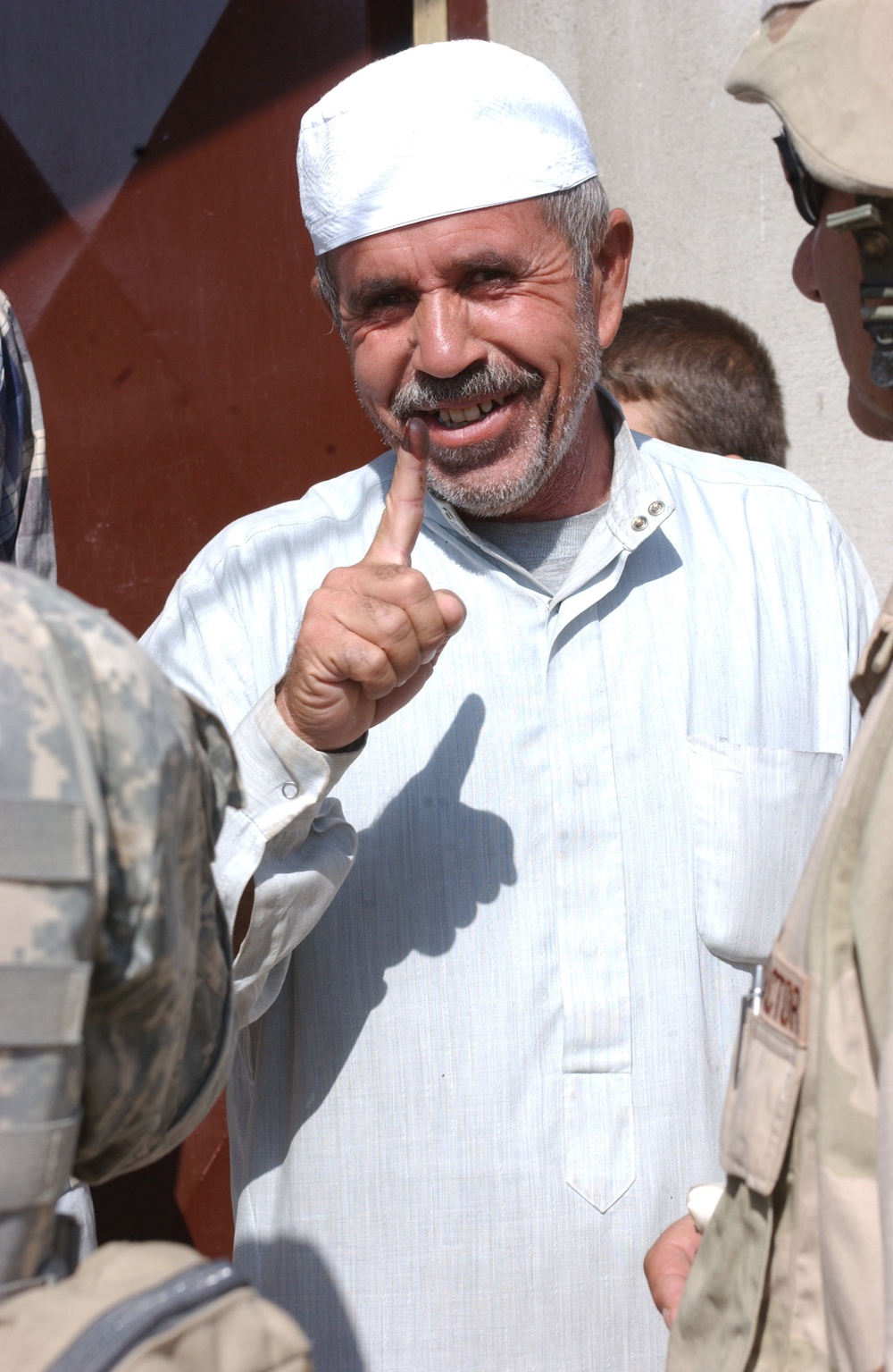 An Iraqi man holds up his finger to show paratroopers that he voted