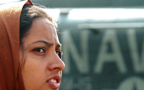 A Pakistani Woman  Watches  as Supplies Are Unloaded From an MH-53 Sea Stal