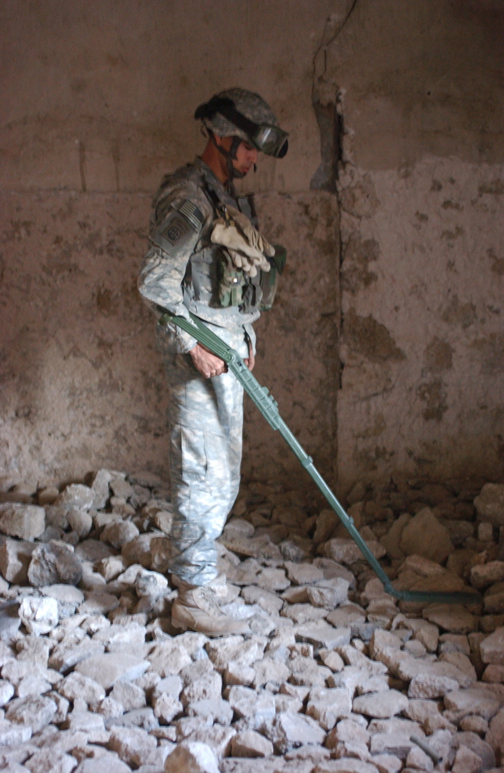 Pfc. Cuellar searches the floor of a house for hidden weapon caches