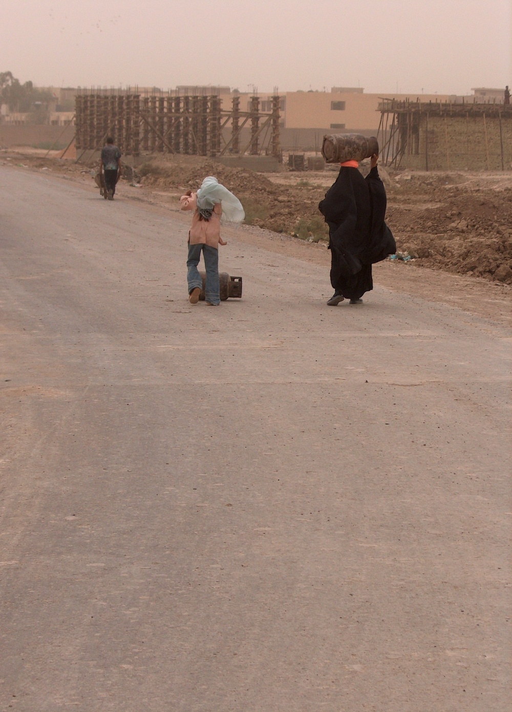 A mother and daughter move two propane tanks down a newly-opened road