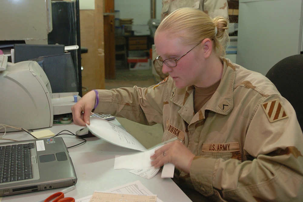 Pvt. Holdwick prepares a dinar check at the finance office