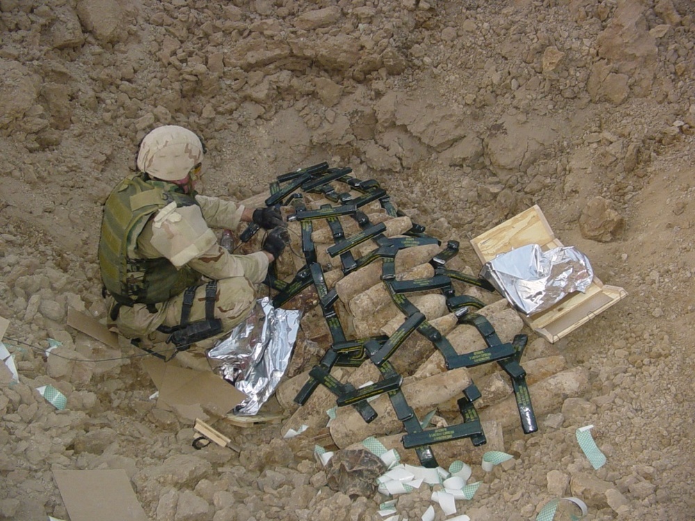 A Soldier prepares a pile of munitions for demolition