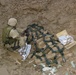 A Soldier prepares a pile of munitions for demolition