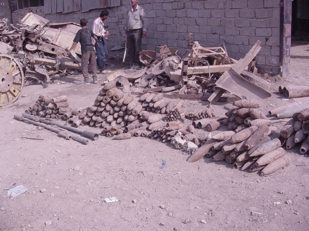 Iraqis look over a pile of unexploded ordnance