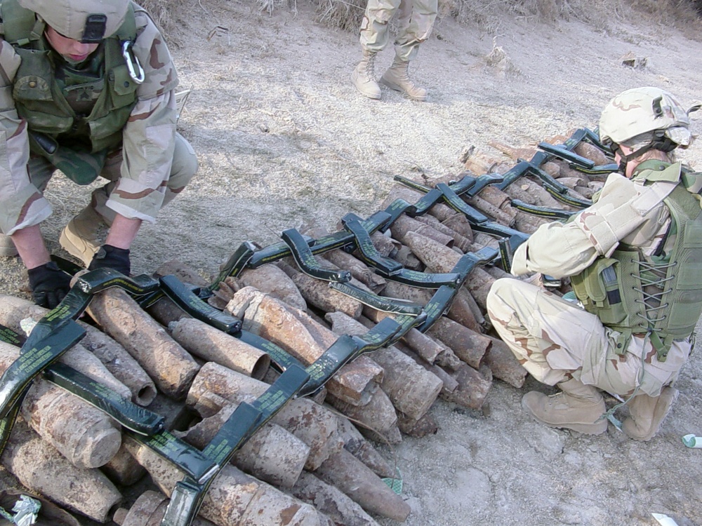 Soldiers prepare a stack of munitions for demolition