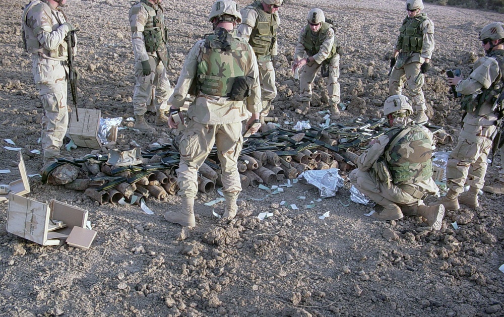 Soldiers sort through a pile of munitions