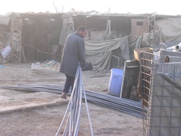 An Abu Ghraib resident helps unload PVC pipes