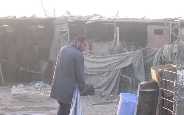 An Abu Ghraib resident helps unload PVC pipes