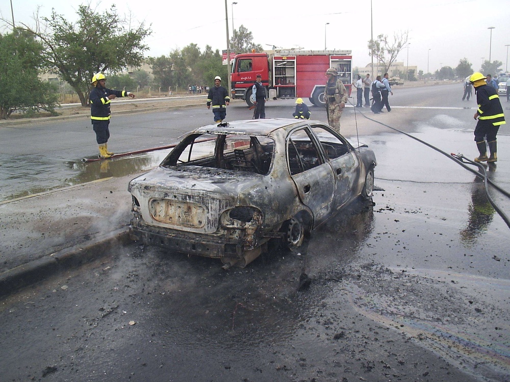 Iraqi firefighters finish putting out a fire after a terrorist rocket attac