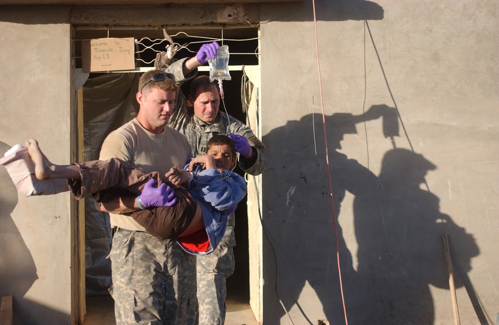 Sgt. Johns carries a young boy who was shot in the foot to a waiting vehicl