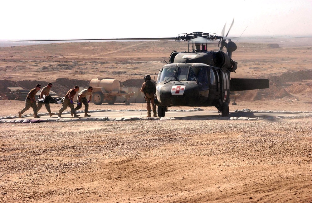 Medics carry a wounded man to a waiting helicopter