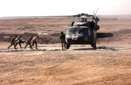 Medics carry a wounded man to a waiting helicopter