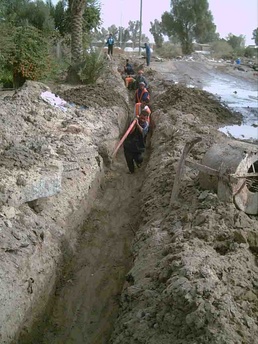 Iraqi workers move cable into a trench