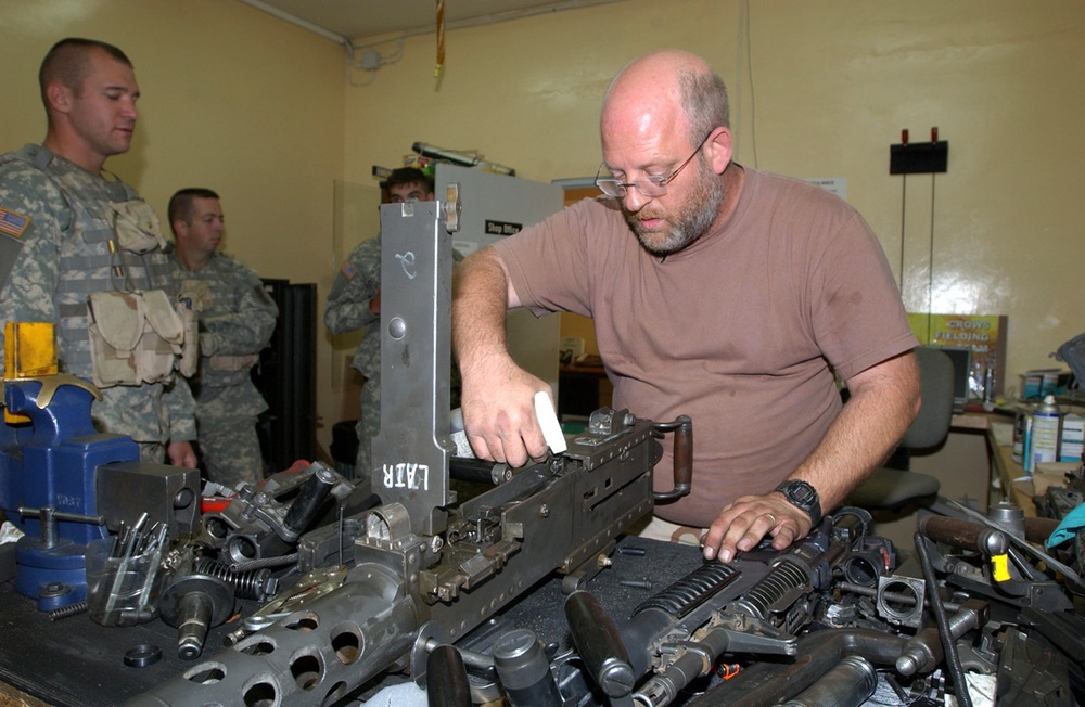 A small arms maintenance technician works on a .50 caliber machine gun