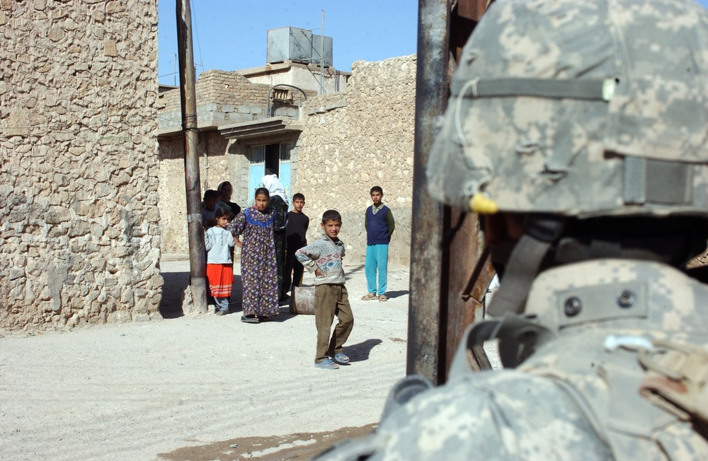 Local residents of Tal Afar watch as a patrol passes by