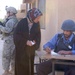 An Iraqi police officer marks a woman's ration card