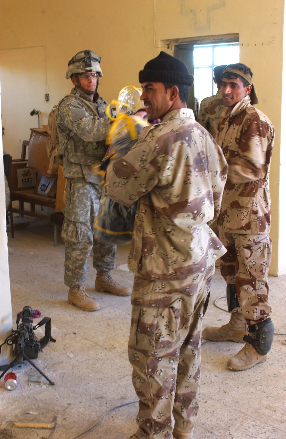 Iraqi army soldiers and U.S. paratroopers unload a truck load of blankets